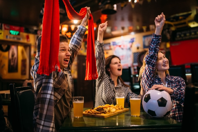 images/football-fans-with-scarf-watching-match-raise-their-hands-up-sports-bar-tv-broadcasting-young-friends-leisures-pub-favorite-team-wins.jpg
